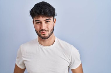 Hispanic man with beard standing over white background looking at the camera blowing a kiss on air being lovely and sexy. love expression. 