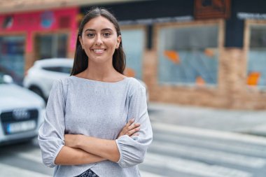 Sokakta kollarını kavuşturmuş genç, güzel İspanyol bir kadın.