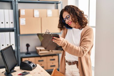 Middle age hispanic woman working speaking on the phone at ecommerce