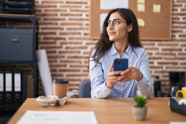 Young hispanic girl business worker using smartphone working at office