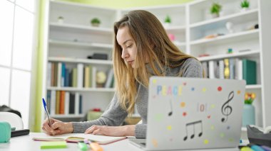 Kütüphanede dizüstü bilgisayar kullanan beyaz bir kız öğrenci.