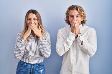 Mavi arka planda dikilen genç çift gülüyor ve utanıyor kıkırdıyor elleri, dedikoduları ve skandal konseptiyle ağzı örtüyor. 