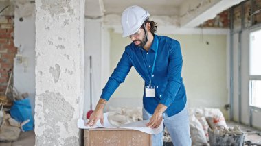 Genç İspanyol mimar inşaat alanının planlarını okuyor.