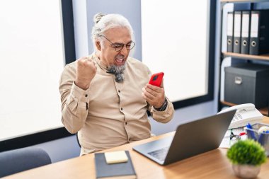 Middle age grey-haired man business worker using smartphone with winner expression at office