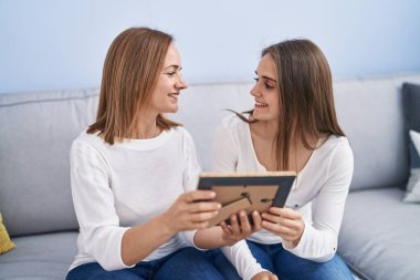 Two women mother and daughter looking photo at home