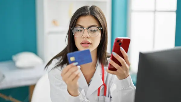 Young caucasian woman doctor shopping with smartphone and credit card at clinic