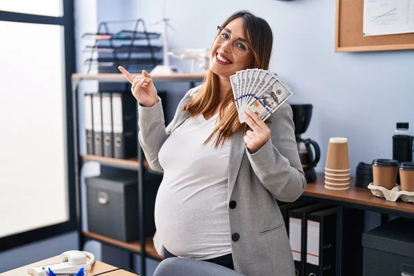Těhotná Žena Drží Dolary Kanceláři Úsměvem Šťastně Ukazuje Rukou Prstem — Stock fotografie