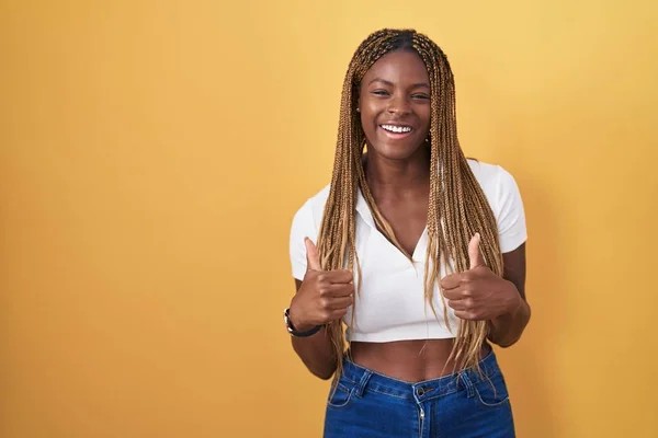 Africká Američanka Vlasy Spletenými Přes Žluté Pozadí Znamení Úspěchu Dělá — Stock fotografie