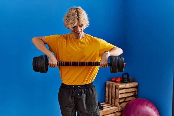 Young blond man smiling confident using weight training at sport center