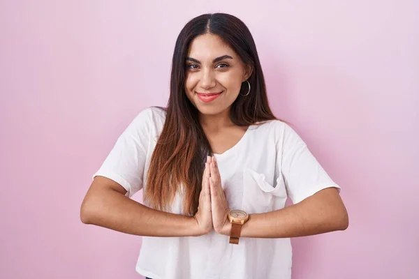 stock image Young arab woman standing over pink background praying with hands together asking for forgiveness smiling confident. 