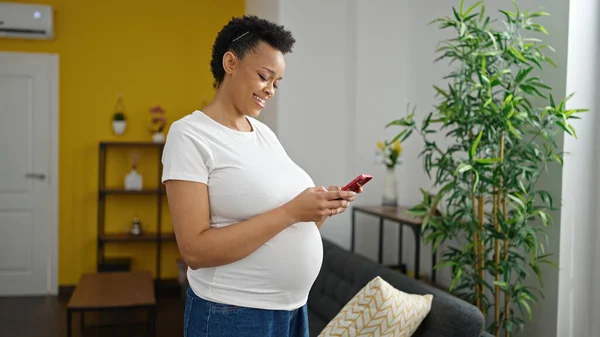 Evde Gülümseyen Akıllı Telefon Kullanan Hamile Bir Kadın — Stok fotoğraf