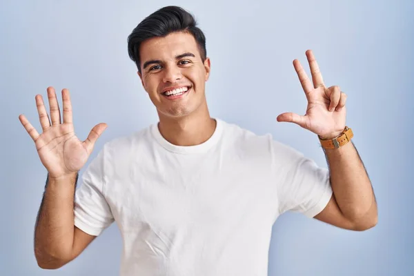自信と幸せ笑みを浮かべている間 ヒスパニック系の男は上に立って青の背景が表示され 指の数8を指して — ストック写真