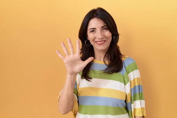中年惊慌失措的女人站在黄色的背景上 用五号手指指指着 满面笑容 自信而快乐 — 图库照片