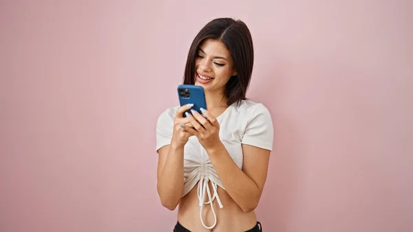 年轻的高加索女人用智能手机对着孤立的粉色背景微笑 — 图库照片