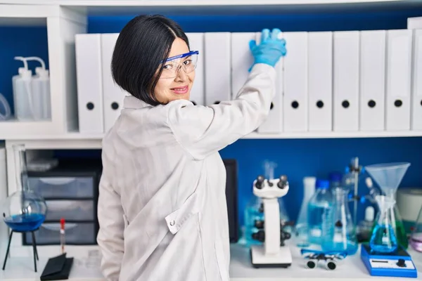 Young chinese woman scientist holding binder at laboratory