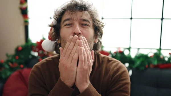 自宅でキスするクリスマスの装飾でソファーに座っている若いヒスパニックの男 — ストック写真