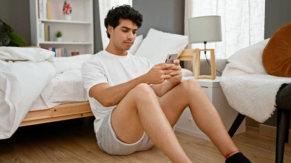 Genç Latin Adam Akıllı Telefon Kullanıyor Yatak Odasında Yerde Oturuyor — Stok fotoğraf