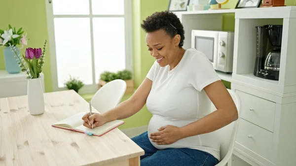 Junge Schwangere Schreibt Auf Notizbuch Und Spürt Baby Tritt Esszimmer — Stockfoto