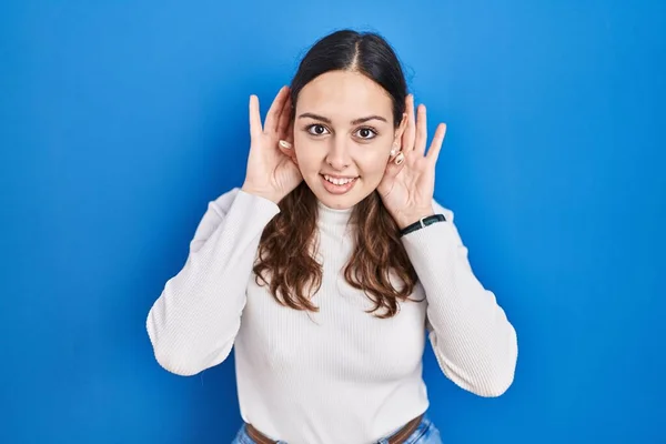 Mujer Hispana Joven Pie Sobre Fondo Azul Tratando Escuchar Ambos —  Fotos de Stock