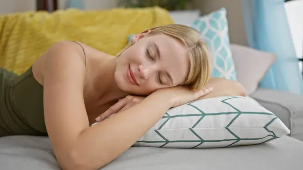 Young blonde woman lying on sofa sleeping at home