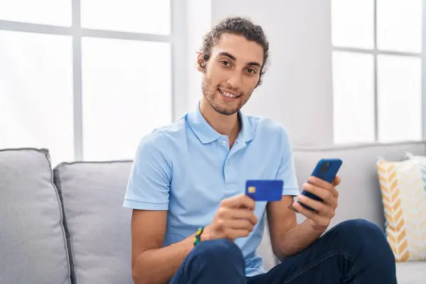 Joven Hombre Hispano Usando Teléfono Inteligente Tarjeta Crédito Sentado Sofá — Foto de Stock