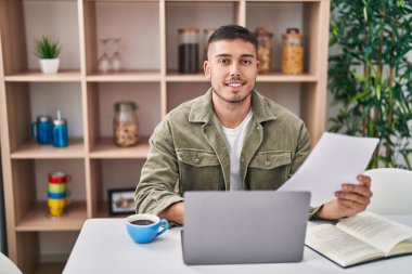 Genç İspanyol adam masada oturmuş, evde ders çalışıyor.