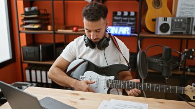 Genç Arap müzisyen müzik stüdyosunda elektro gitar çalıyor.