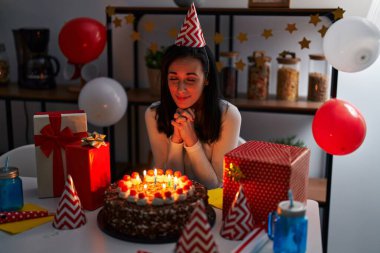 Young caucasian woman celebrating birthday sitting on table at home