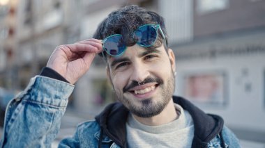 Young hispanic man smiling confident wearing sunglasses at street