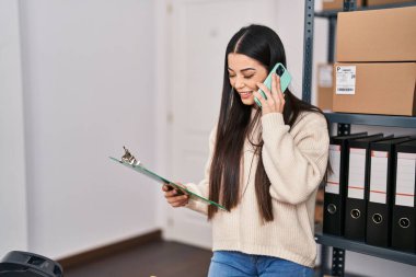 Genç, güzel, İspanyol bir kadın. İşadamı, ofisteki akıllı telefon okuma belgeleriyle konuşuyor.