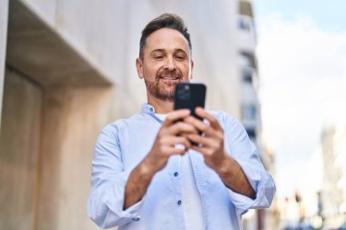 Young caucasian man smiling confident using smartphone at street