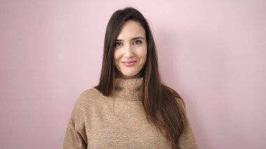 Güzel İspanyol kadın pembe arka planda kendine güvenen gülümsüyor.