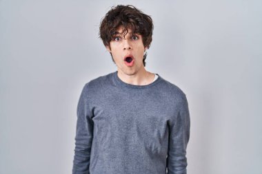 Young man standing over isolated background afraid and shocked with surprise and amazed expression, fear and excited face. 