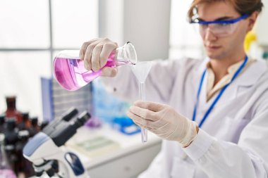 Kafkasyalı genç bilim adamı laboratuarda test tüpüne sıvı döküyor.