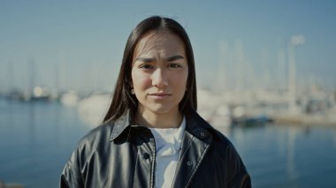 Genç ve güzel İspanyol kadın deniz kenarında ciddi bir ifadeyle ayakta duruyor.