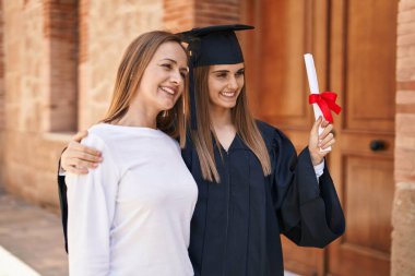 Two women mother and graduated daughter standing together at campus university