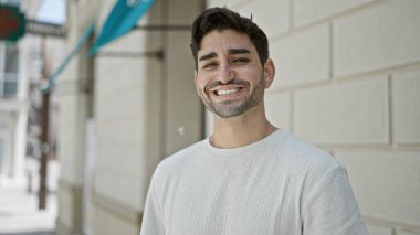 Sokakta kendinden emin gülümseyen İspanyol genç adam.