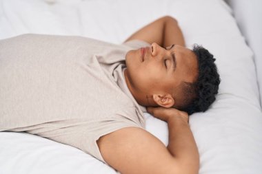 Genç latin adam yatakta uzanıyor, yatak odasında uyuyor.