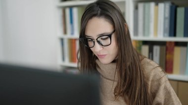 Güzel İspanyol kadın öğrenci kütüphane üniversitesinde bilgisayar kullanıyor.