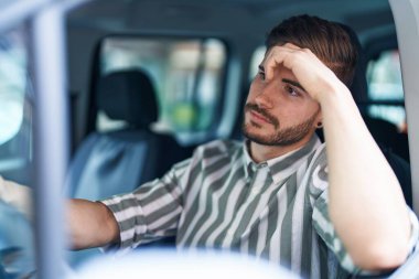 Young caucasian man stressed driving car at street