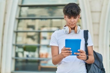 Latin kökenli genç bir öğrenci üniversitede rahat bir ifadeyle dokunmatik ped kullanıyor.