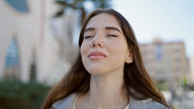 Sokakta gözleri kapalı duran genç İspanyol kadın.