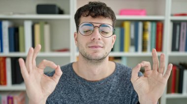 Genç İspanyol öğrenci kütüphane üniversitesinde meditasyon yapıyor.