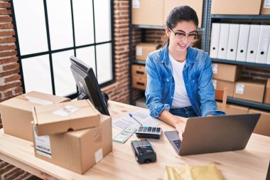 Young beautiful hispanic woman ecommerce business worker using laptop working at office
