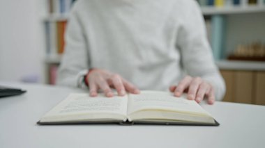 Genç İspanyol adam üniversite sınıfında oturmuş kitap okuyor.