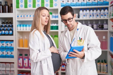 Erkek ve kadın eczacılar eczanede dokunmatik ped kullanıyorlar.