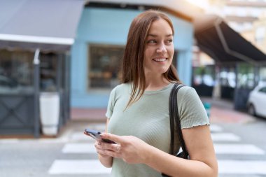 Sokakta akıllı telefon kullanan kendine güvenen güzel bir kadın.