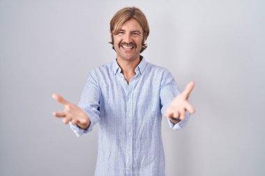 Beyaz arka planda duran beyaz bıyıklı, neşeli gülümsemeli, yardım eli uzatan ve kabul eden beyaz bir adam.. 