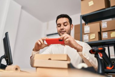 Genç İspanyol bir e-ticaret işçisi ofiste fotoğraf paket yapıyor.