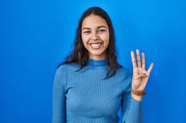 Mavi arka planda duran Brezilyalı genç bir kadın dört numarayı gösterip işaret ederken kendinden emin ve mutlu gülümsüyor.. 